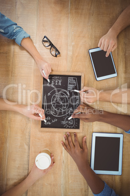 Close-up of cropped hands writing business terms on slate with p