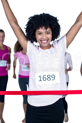 Portrait of happy winner female athlete crossing finish line wit