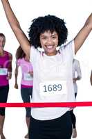 Portrait of happy winner female athlete crossing finish line wit