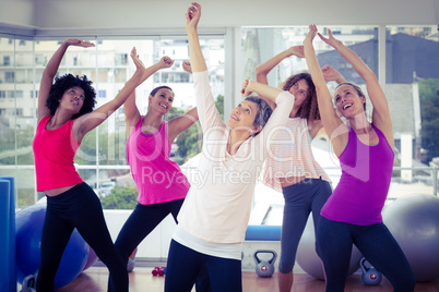 Happy women exercising with arms raised while looking up