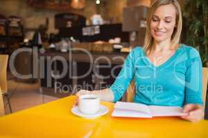 Young woman holding book with coffee cup