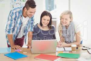 Happy colleagues working on laptop