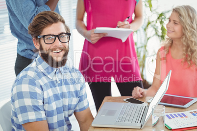 Portrait of smiling man with coworkers discussing