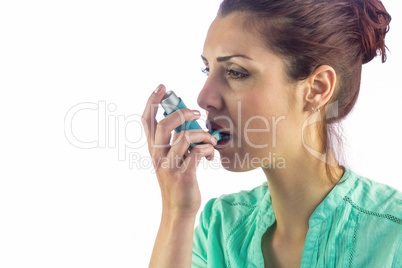 Woman looking away while using asthma inhaler
