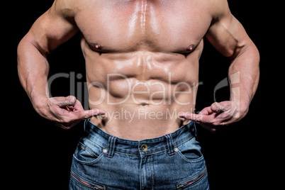 Midsection of shirtless man pointing at abs