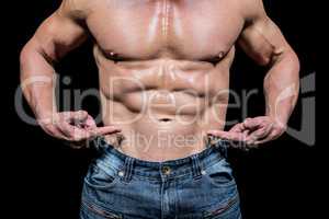 Midsection of shirtless man pointing at abs