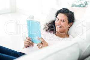 Pregnant woman smiling while reading book
