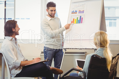 Confident businessman giving presentation as colleagues looking