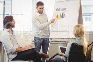 Confident businessman giving presentation as colleagues looking