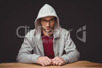 Thoughtful man with hooded shirt sitting at desk