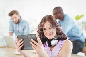 Portrait of smiling woman with headphones while using digital ta