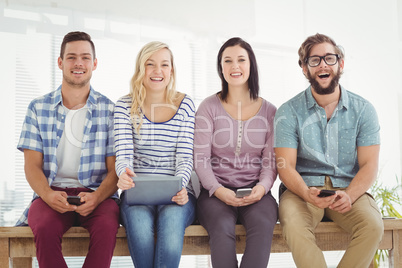 Portrait of smiling business people holding electronic gadgets