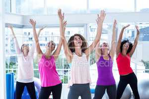 Portrait of happy women exercising with arms raised