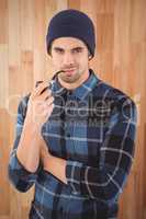 Portrait of confident hipster smoking pipe