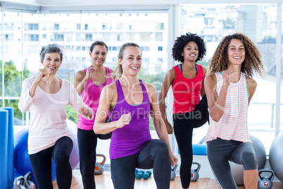 Portrait of smiling women exercising with clasped hands