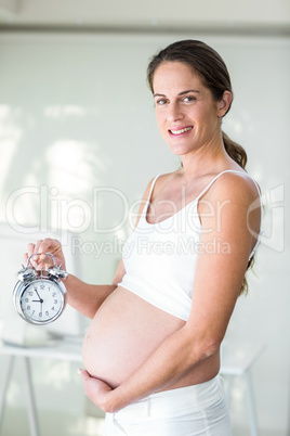 Portrait of happy woman holding alarm clock
