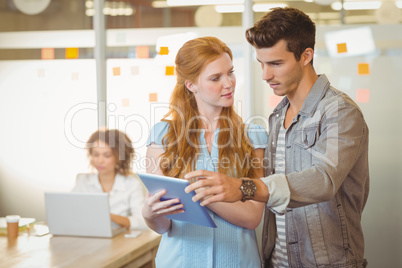 Businesswoman showing digital PC to businessman