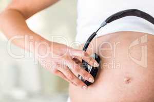Close-up of woman with headphones on belly