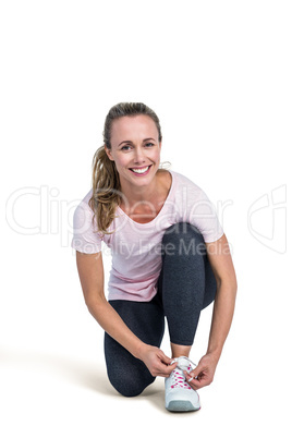 Portrait of happy sporty woman tying shoelace