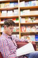 Concentrated young man reading book in library