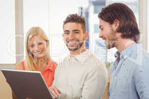 Businessman using laptop as colleagues looking at it