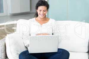 Happy woman with laptop on sofa