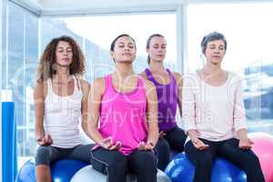 Women relaxing on exercise balls with eyes closed