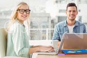 Portrait of happy woman wearing eyeglasses working on laptop wit