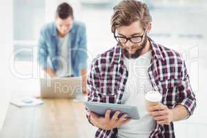 Businessman using digital tablet and holding coffee cup