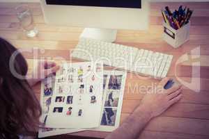 Hipster holding photographs working at computer desk