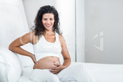 Portrait of happy pregnant woman touching tummy