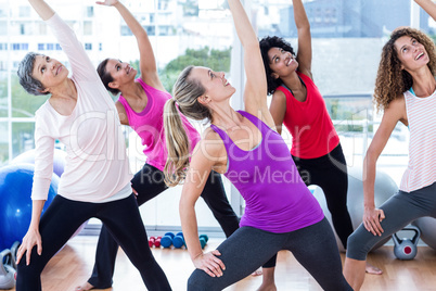 Smiling women exercising with arms raised while looking up