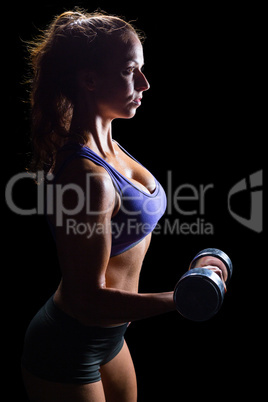 Side view of sexy woman lifting dumbbell