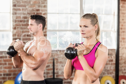 muscular serious couple with kettlebells