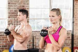 muscular serious couple with kettlebells