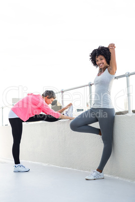 Happy young woman stretching with female friend