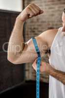 Muscular man measuring biceps