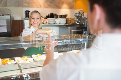 Female shop owner giving sandwich to customer