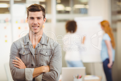 Businessman with arms crossed standing against colleagues