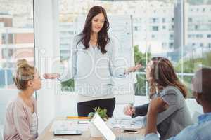 Woman gesturing while discussing with coworkers