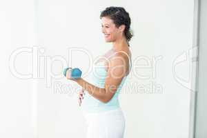 Happy pregnant woman lifting dumbbells