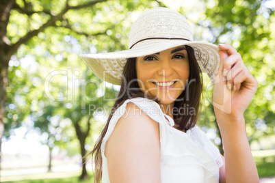 Portrait of cheerful woman holding sun hat