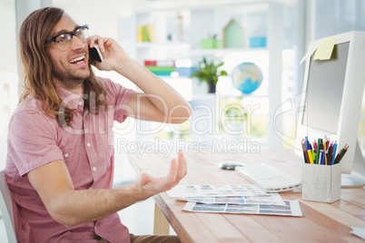 Happy hipster talking on mobile phone in office