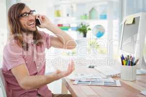Happy hipster talking on mobile phone in office