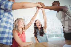Smiling business people giving high five at desk