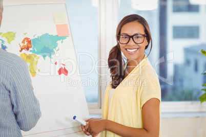 Businesswoman with male colleague standing near world map on whi