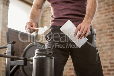 Midsection of man adding supplement to bottle