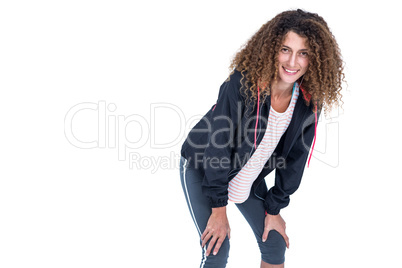 Happy young woman bending with hand on knee