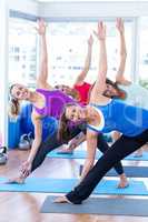 Cheerful women in fitness studio doing side stretch