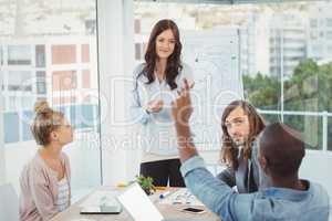 Rear view of man with hand raised while discussing with coworker